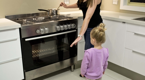 A woman teaching a child about oven safety