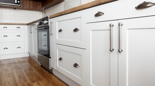 Stylish light gray handles on cabinets close-up, kitchen interior with modern furniture and stainless steel appliances. kitchen design in scandinavian style