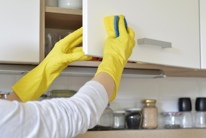 woman in yellow gloves cleaning gloss kitchen cabinet cupboard