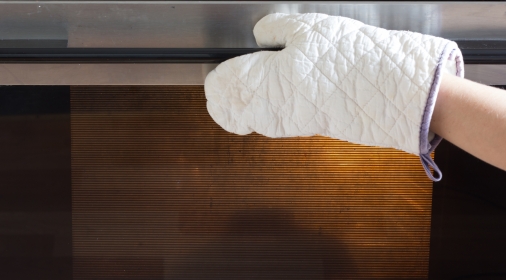 Woman hand in potholder opening the oven door