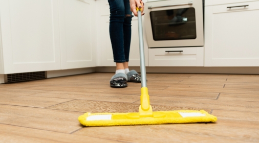 woman washes wooden floors from a laminate floor in a bright kitchen.