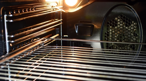 The inside of an empty oven with oven light bulb