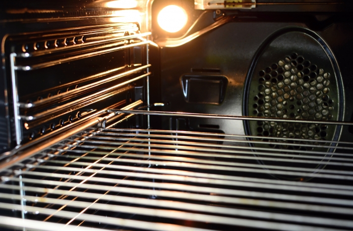 The inside of an empty oven with oven light bulb