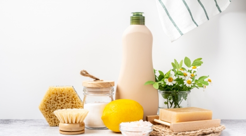 Eco friendly natural cleaners, jar with baking soda, dish brush, lemon, flowers, soap on white background. Organic ingredients for homemade cleaning with mock up bottle. Zero waste concept, copy space