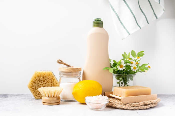 Eco friendly natural cleaners, jar with baking soda, dish brush, lemon, flowers, soap on white background. Organic ingredients for homemade cleaning with mock up bottle. Zero waste concept, copy space