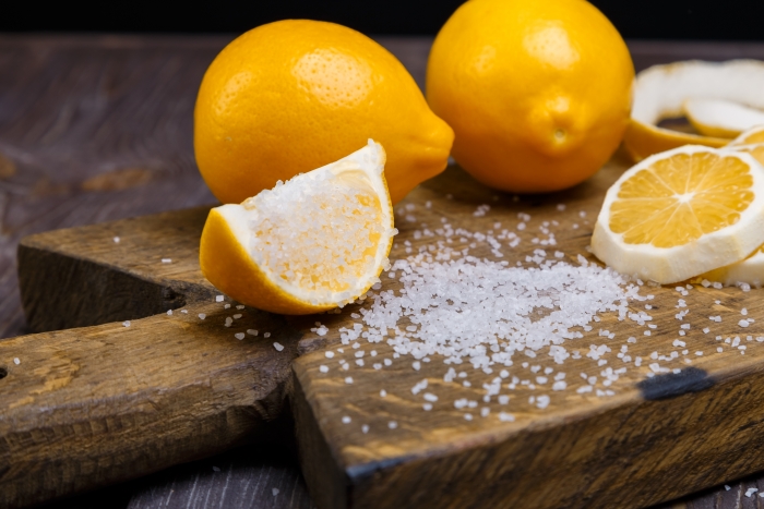 some sliced lemons on a wooden cutting board and sea salt