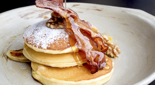 Stack of delicious pancakes with bacon, honey, nuts and caramelize banana