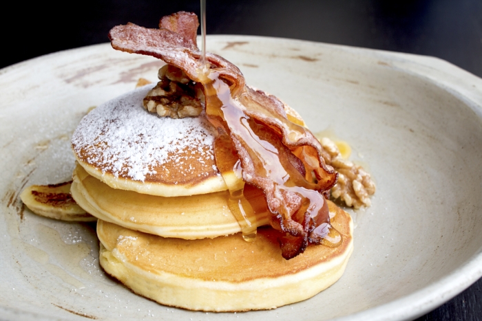 Stack of delicious pancakes with bacon, honey, nuts and caramelize banana