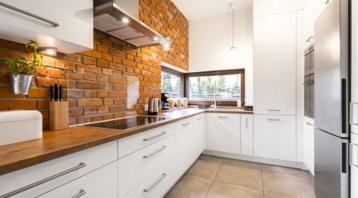 Brick wall in spacious modern designed white kitchen with marble floor