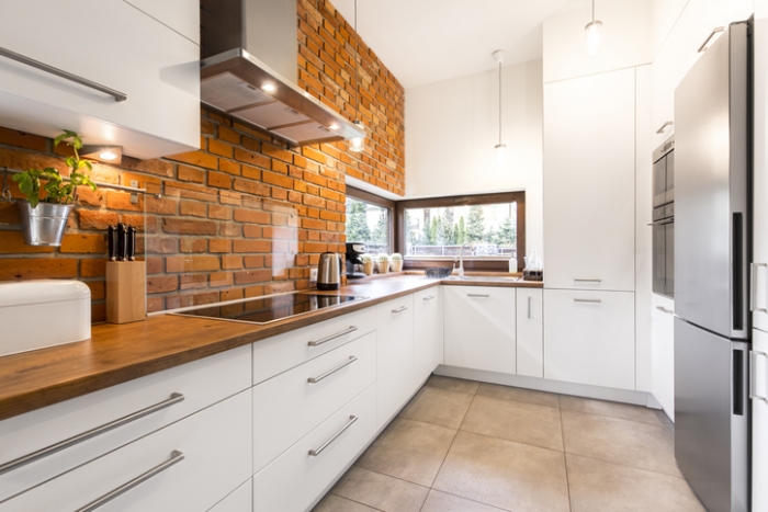 Brick wall in spacious modern designed white kitchen with marble floor