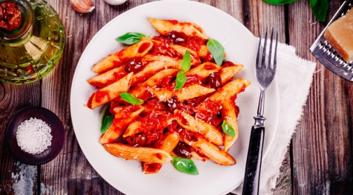 Italian penne pasta with tomato sauce, olives and basil