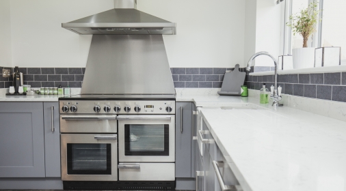 Bright white and grey tiled kitchen with large range cooker and extractor fan