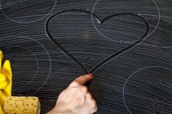 Female finger draws a heart on a oven hob covered with soap