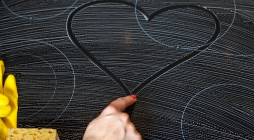 Female finger draws a heart on a oven hob covered with soap