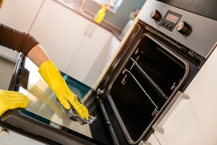 Woman cleaning an oven door