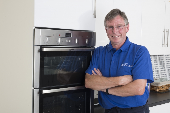 oven cleaning specialist in uniform next to double oven